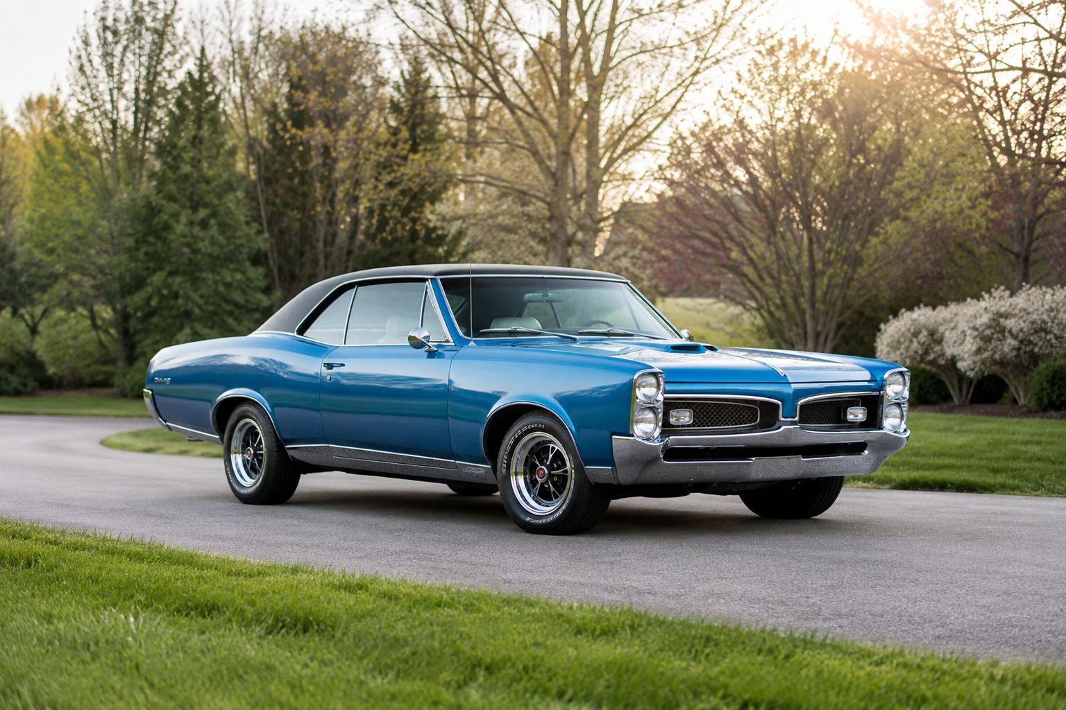 Alt text: Classic blue Pontiac GTO parked on a quiet road in a landscaped setting.