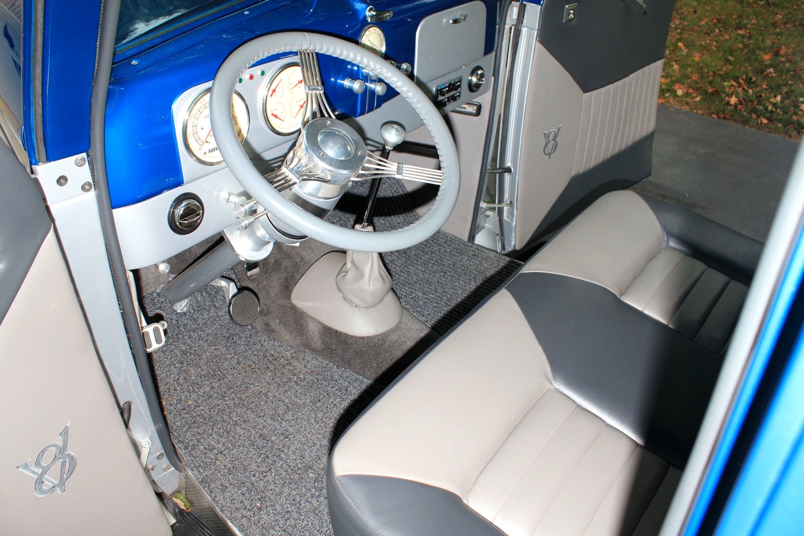 Custom blue automobile interior showing the steering wheel, gauges, dashboard, upholstery, and driver controls.