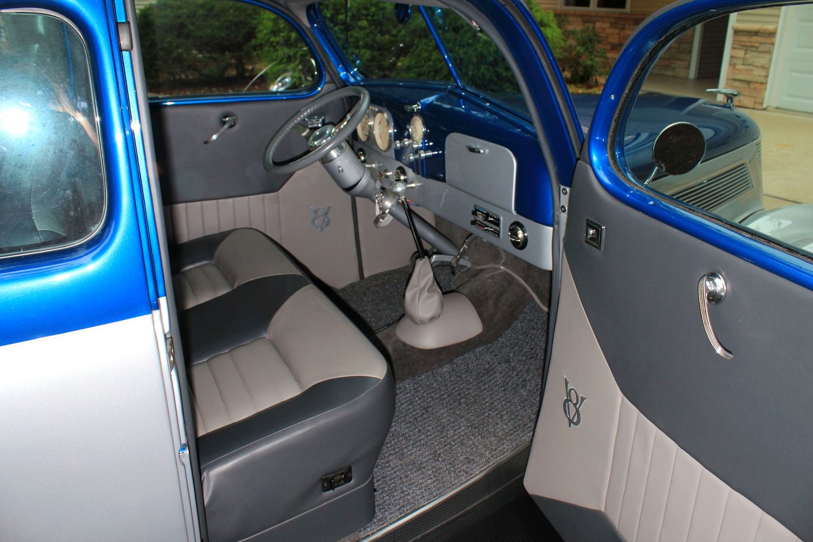 Wide view of a custom blue automobile interior showing the seats, dashboard, steering wheel, door panels, and upholstery.