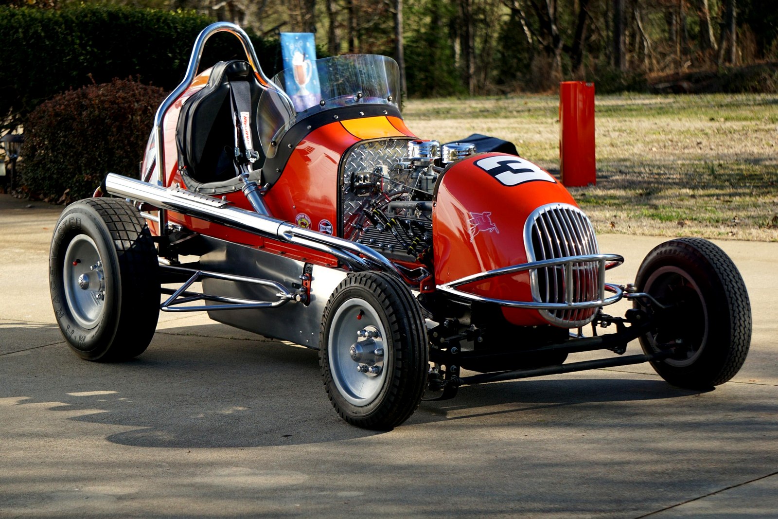 Red vintage open-wheel race car with exposed engine, chrome exhaust, roll bar, and racing number.